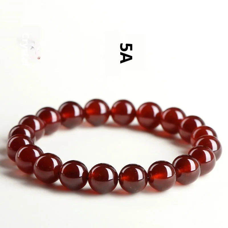Natural orange red garnet ball bracelet with crystal beads and Ruyi design on a wrist.