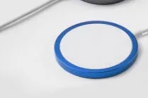 Silver aluminium MagSafe-compatible magnetic wireless charger for iPhone on a wooden desk.