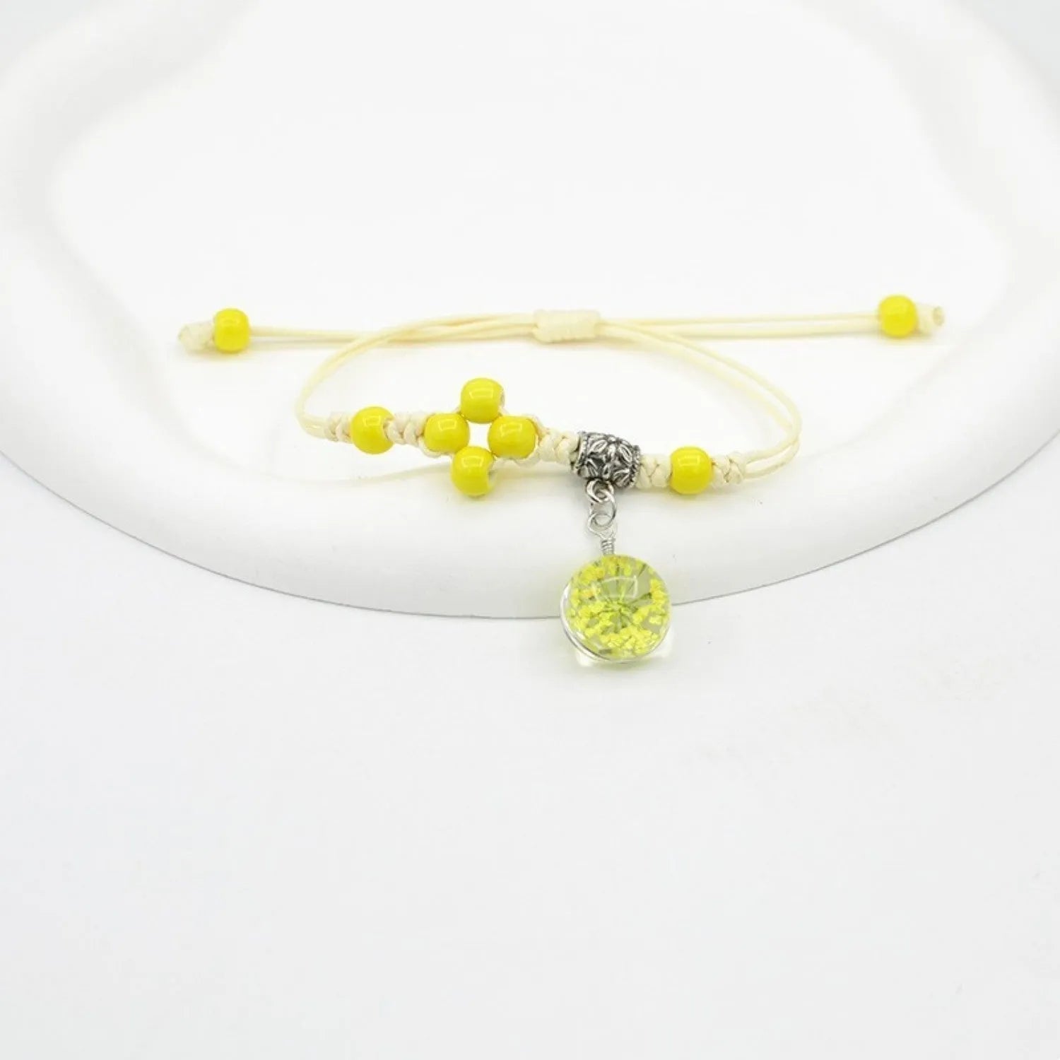 Close-up of a hand-woven glass bracelet with large 1.4cm beads containing real dried flowers and lace floral detailing.