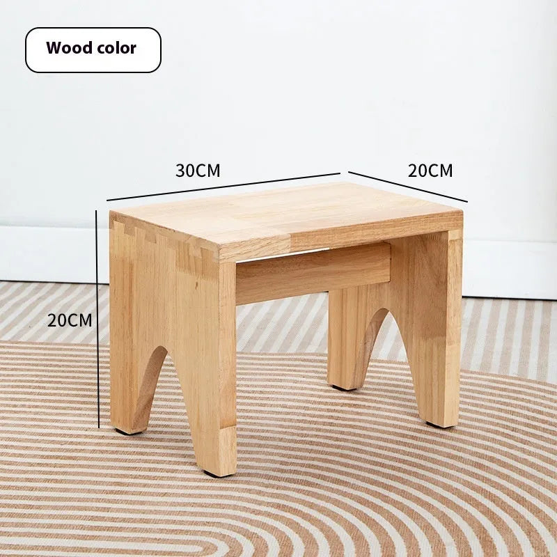 Distressed solid wood shoe changing stool with rustic bracket structure.
