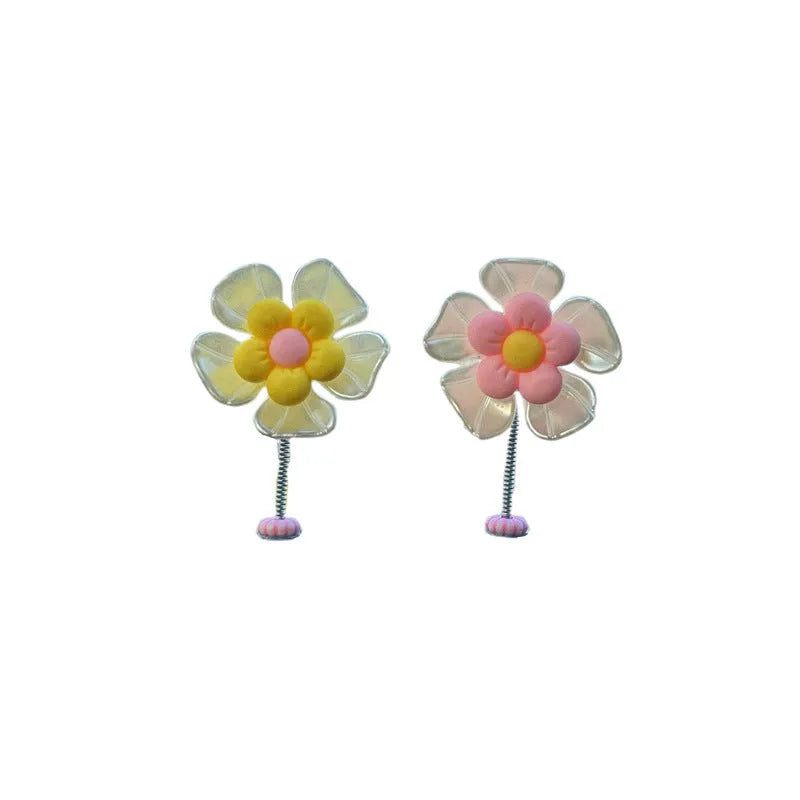 Small colourful plastic swing car decoration hanging from a rear-view mirror, showing blue, green, pink, purple, and yellow colour options.