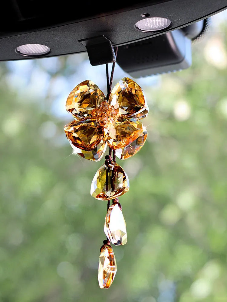 Crystal four leaf clover car pendant hanging, shown in one of four colour options: transparent, champagne, translucent black, or extremely shiny.