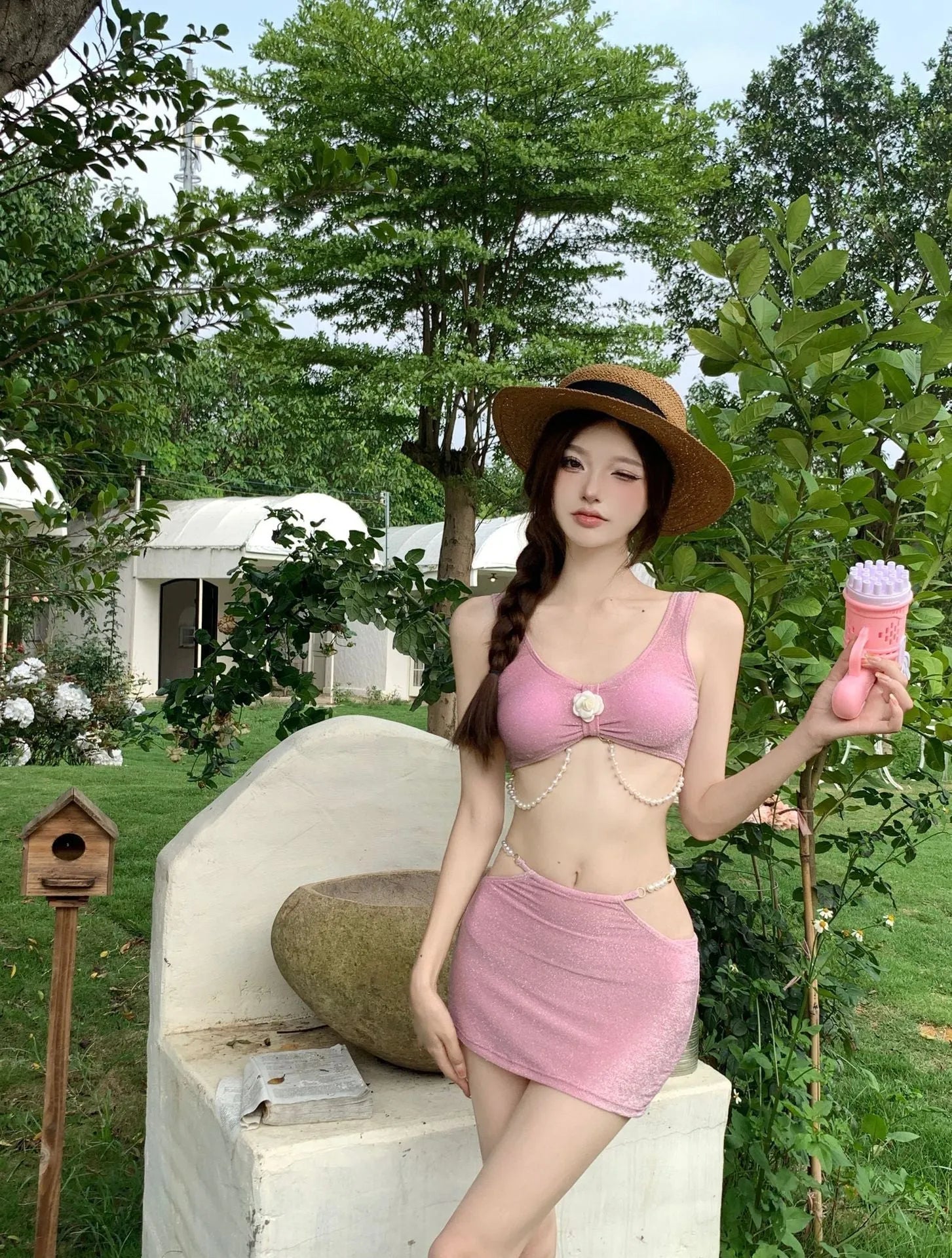 Pink and black three-piece bikini set on a hanger, showing briefs style and sleeveless design.