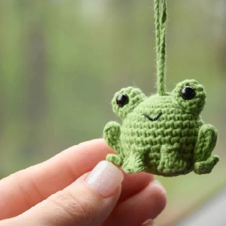 Handmade green plush frog car pendant hanging, showing woven cord and cartoon style.
