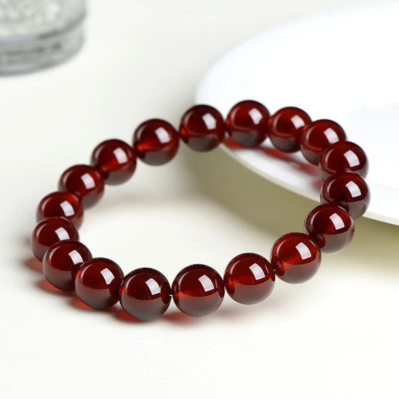 Natural orange red garnet ball bracelet with crystal beads and Ruyi design on a wrist.