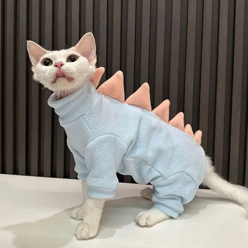 Green fleece dinosaur costume on a hairless Sphynx cat, showing tail and spine details.