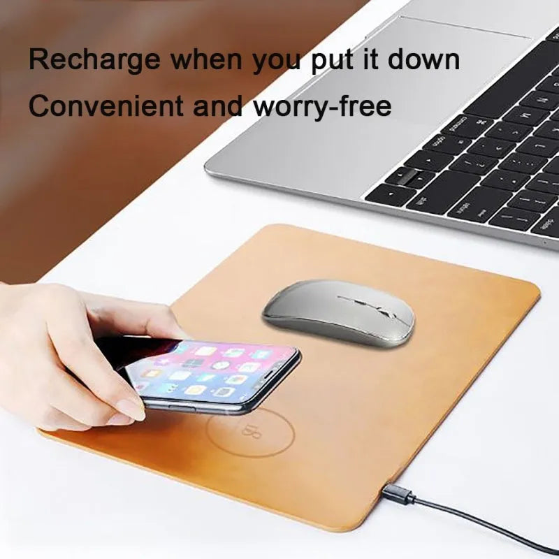 Brown leather wireless charging mouse pad on a wooden desk with a smartphone charging on its surface.