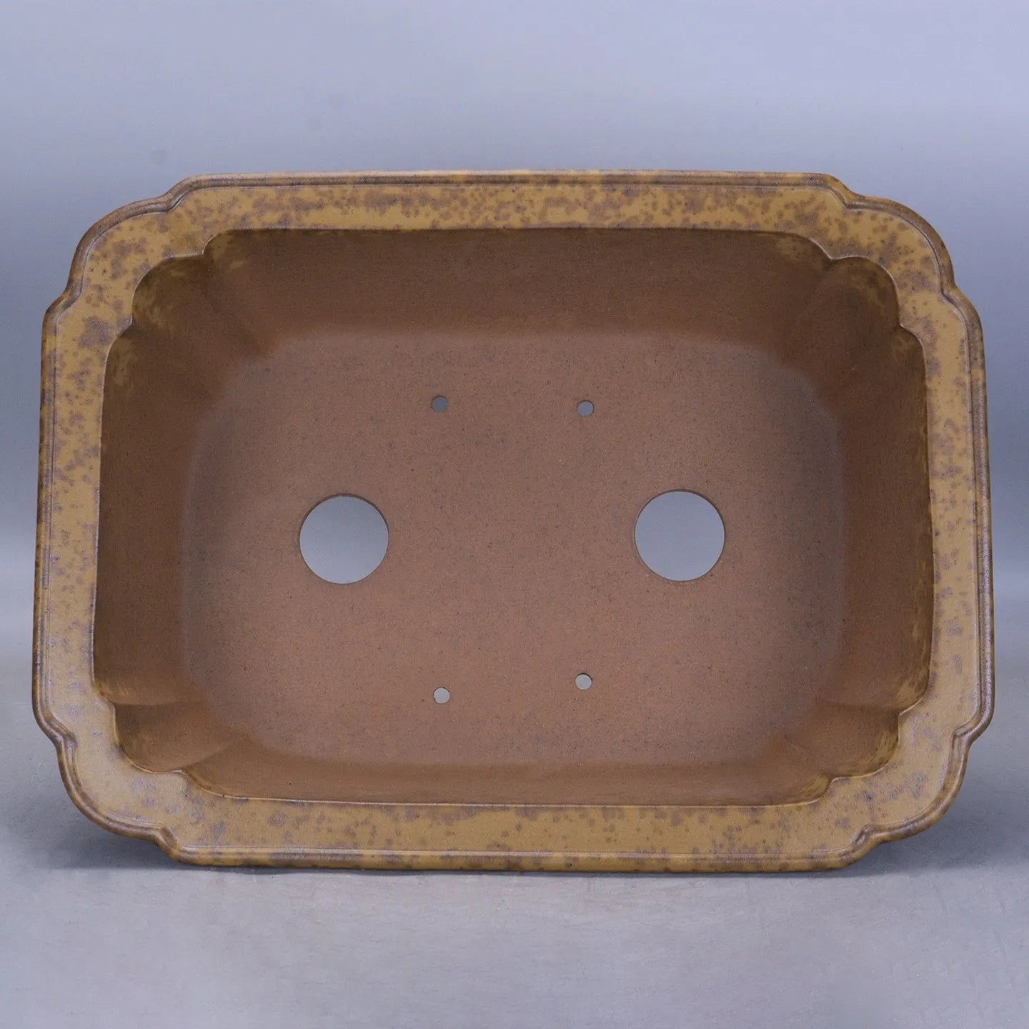 Hand-thrown rectangular purple sand flower pot with dual drainage holes on a wooden deck.