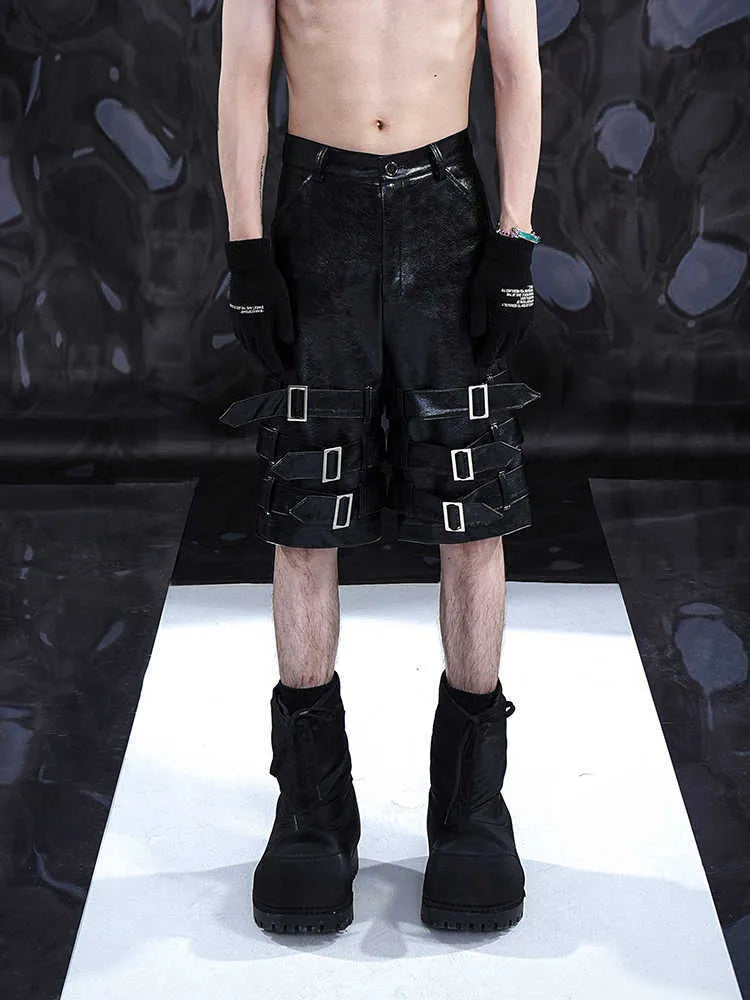 Man wearing black cropped PU leather shorts with a distinctive ring detail on the leg.