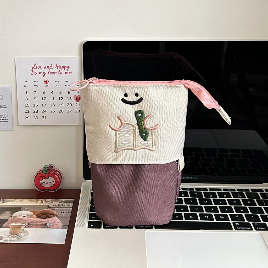 Brown Korean style cartoon print collapsible oxford fabric pencil case open on a table.