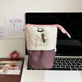 Brown Korean style cartoon print collapsible oxford fabric pencil case open on a table.