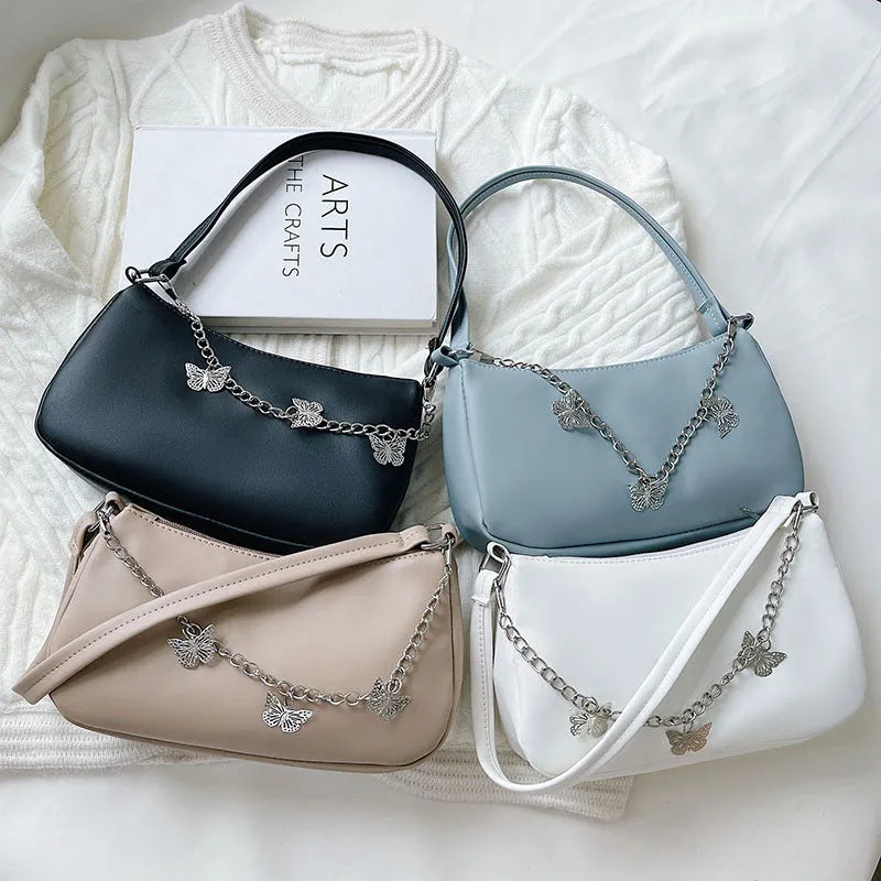 Retro-style light blue underarm shoulder bag with a silver butterfly chain strap, shown worn crossbody.