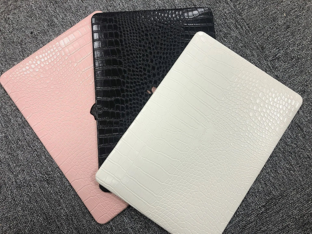 MacBook laptop case in soft pink with a textured crocodile pattern and a hollowed-out Apple logo on the lid.