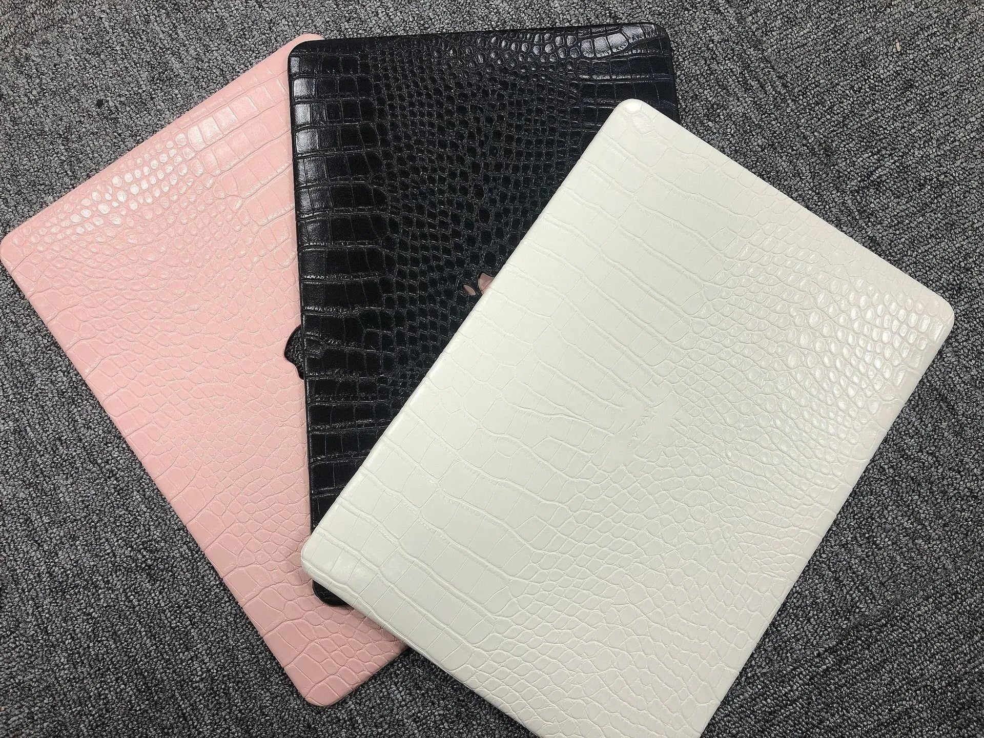 MacBook laptop case in soft pink with a textured crocodile pattern and a hollowed-out Apple logo on the lid.