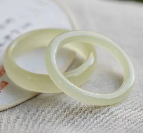 A close-up of a winding jade bracelet made from round bar beads on a wrist.