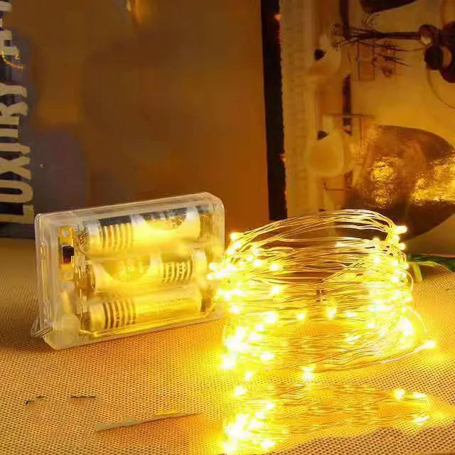 Close-up of flexible copper wire string light with 120 tiny LED bulbs, shaped in a spiral next to the battery control box.