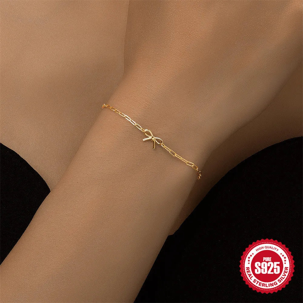 Close-up of a women's sterling silver bracelet with a glossy gold heart charm and lobster clasp.
