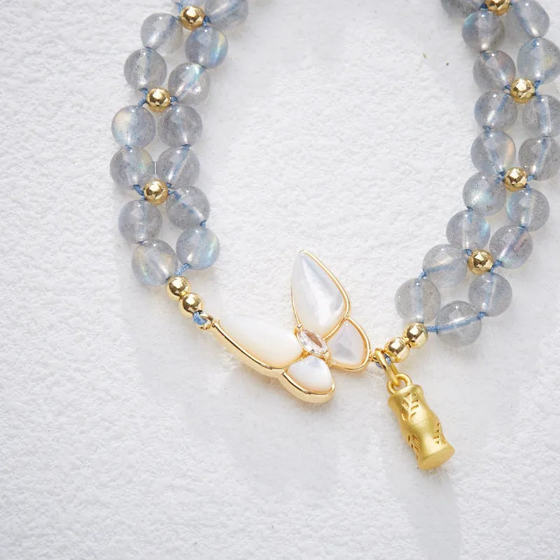 Grey moonstone butterfly charm on a handwoven cord bracelet for women.
