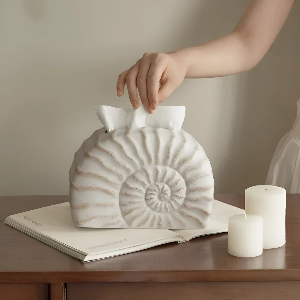 White conch ramble shell design resin tissue box holder on a table.
