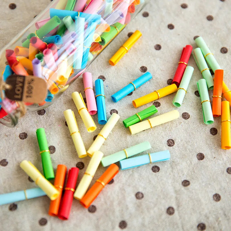 Colourful miniature paper scrolls for drift bottle messages with central eyelet for string attachment