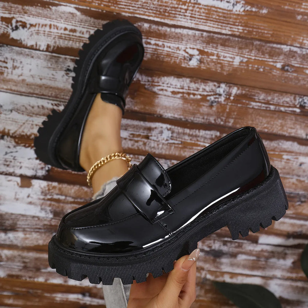 A pair of black plus size slip-on loafers with a chunky mid-heel and thick rubber sole on a plain background.
