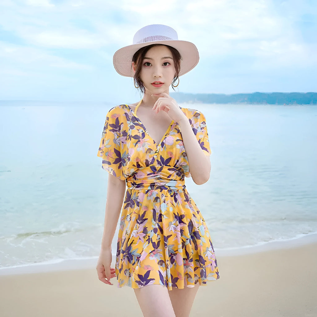 Yellow floral print women's one-piece swimsuit with skirted design on mannequin.