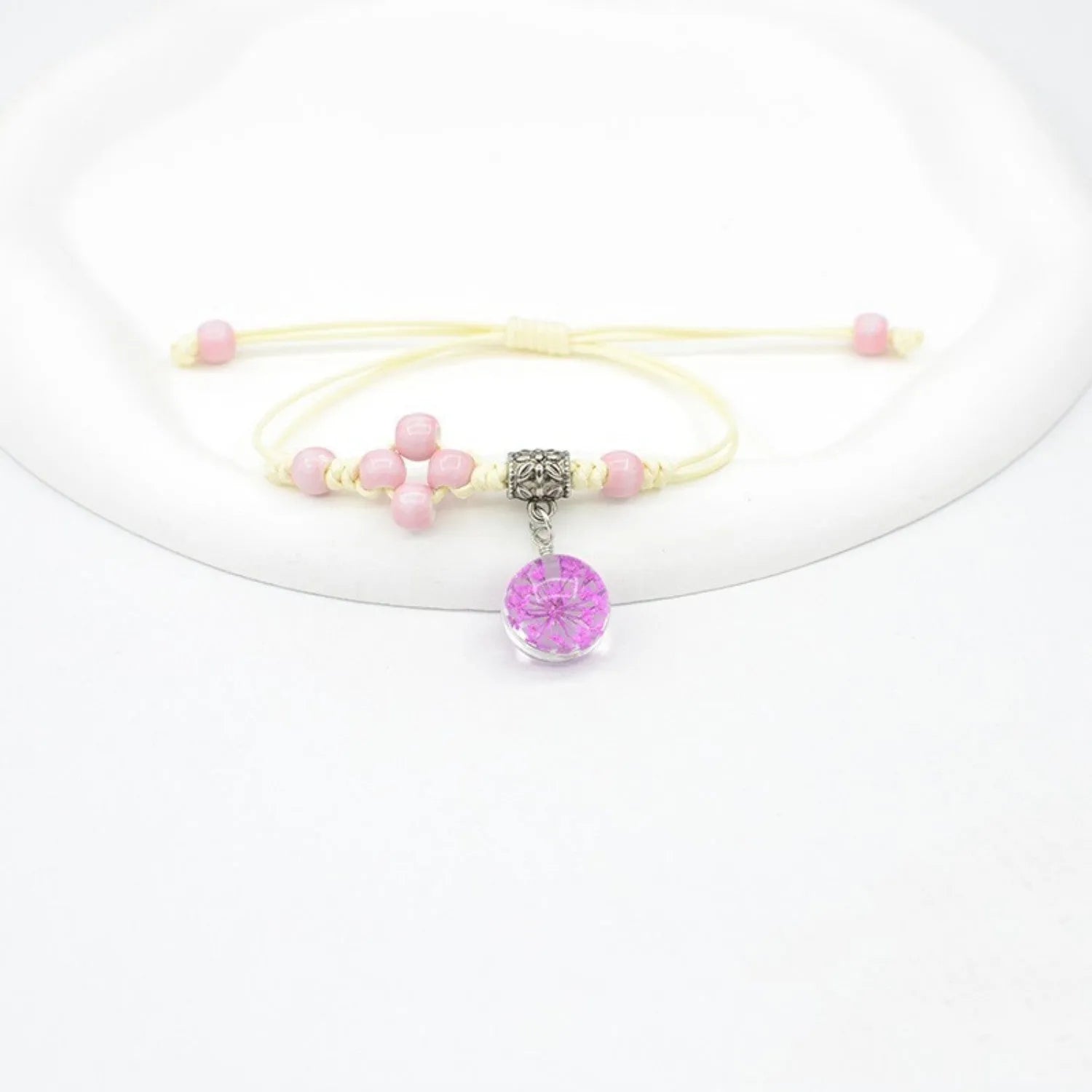 Close-up of a hand-woven glass bracelet with large 1.4cm beads containing real dried flowers and lace floral detailing.