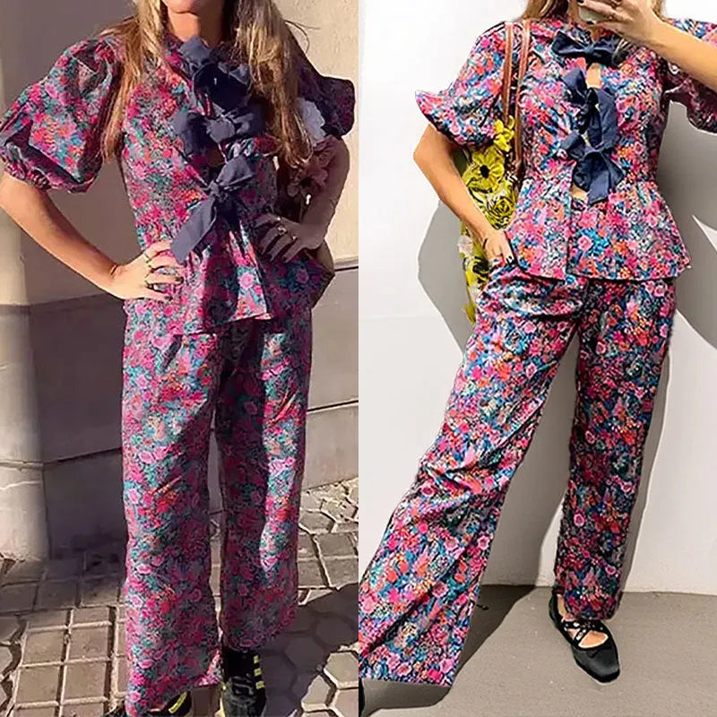 Women's floral print polyester trousers suit with tie-neck blouse and puff sleeves.