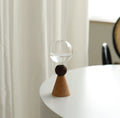 Small clear geometric bubble glass vase on a wooden base, shown with a single flower stem.