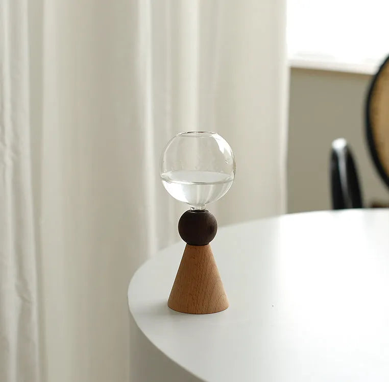 Small clear geometric bubble glass vase on a wooden base, shown with a single flower stem.