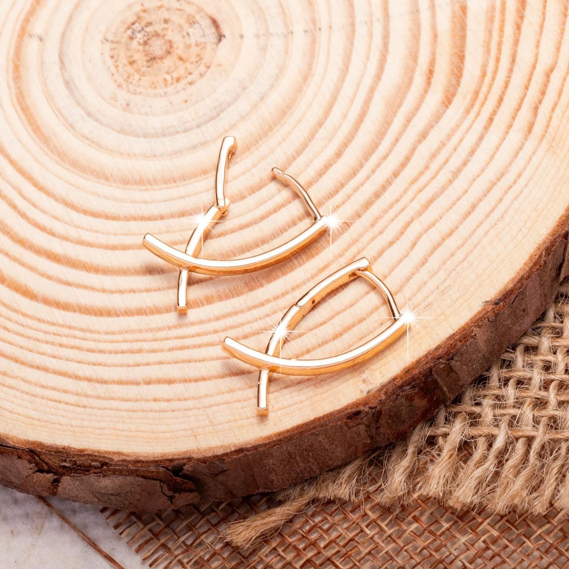 Close-up of a pair of rose gold cross drop earrings on a white background, showing post fittings.