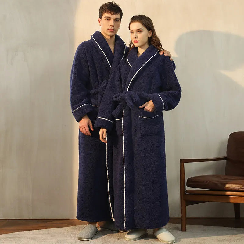 A man and woman wearing matching thick navy blue flannel bathrobes in a cosy winter home setting.