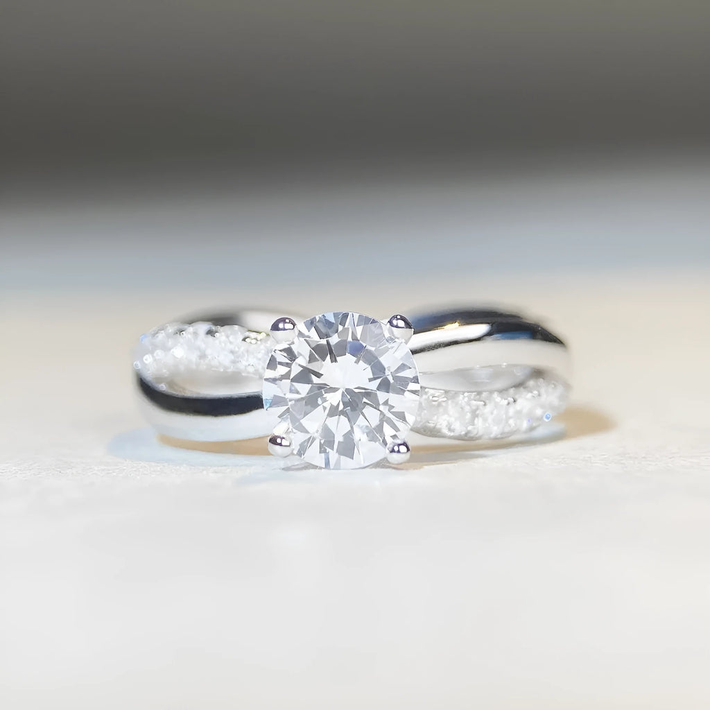 Geometric twisted silver band ring with a 1 carat round moissanite stone in a four-claw setting.