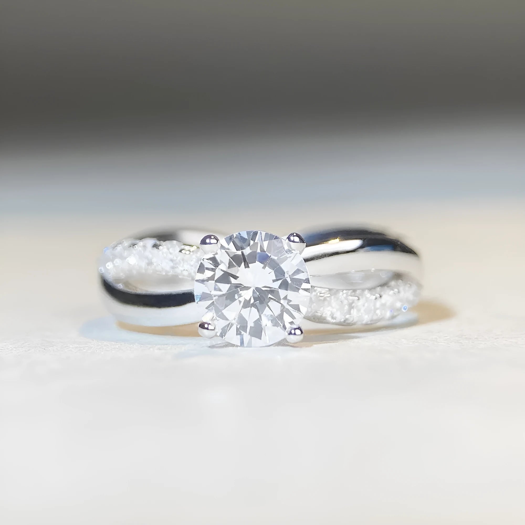 Geometric twisted silver band ring with a 1 carat round moissanite stone in a four-claw setting.