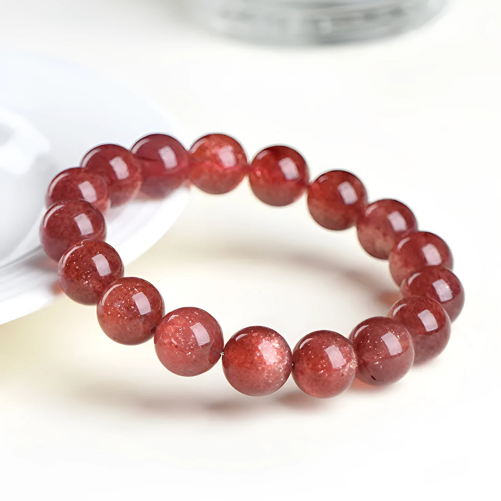 Cherry red strawberry quartz crystal bracelet with geometric beads on a wrist.