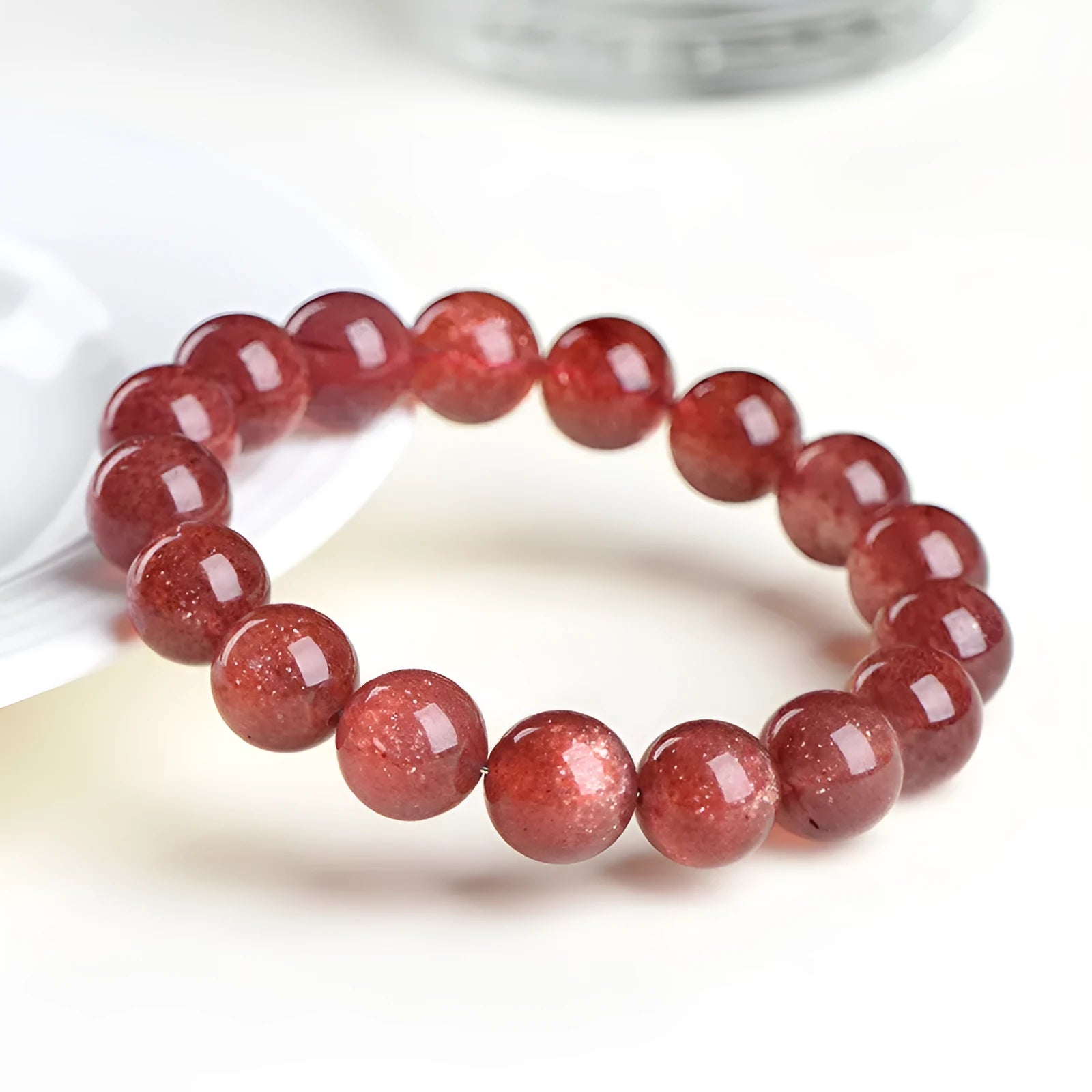 Cherry red strawberry quartz crystal bracelet with geometric beads on a wrist.