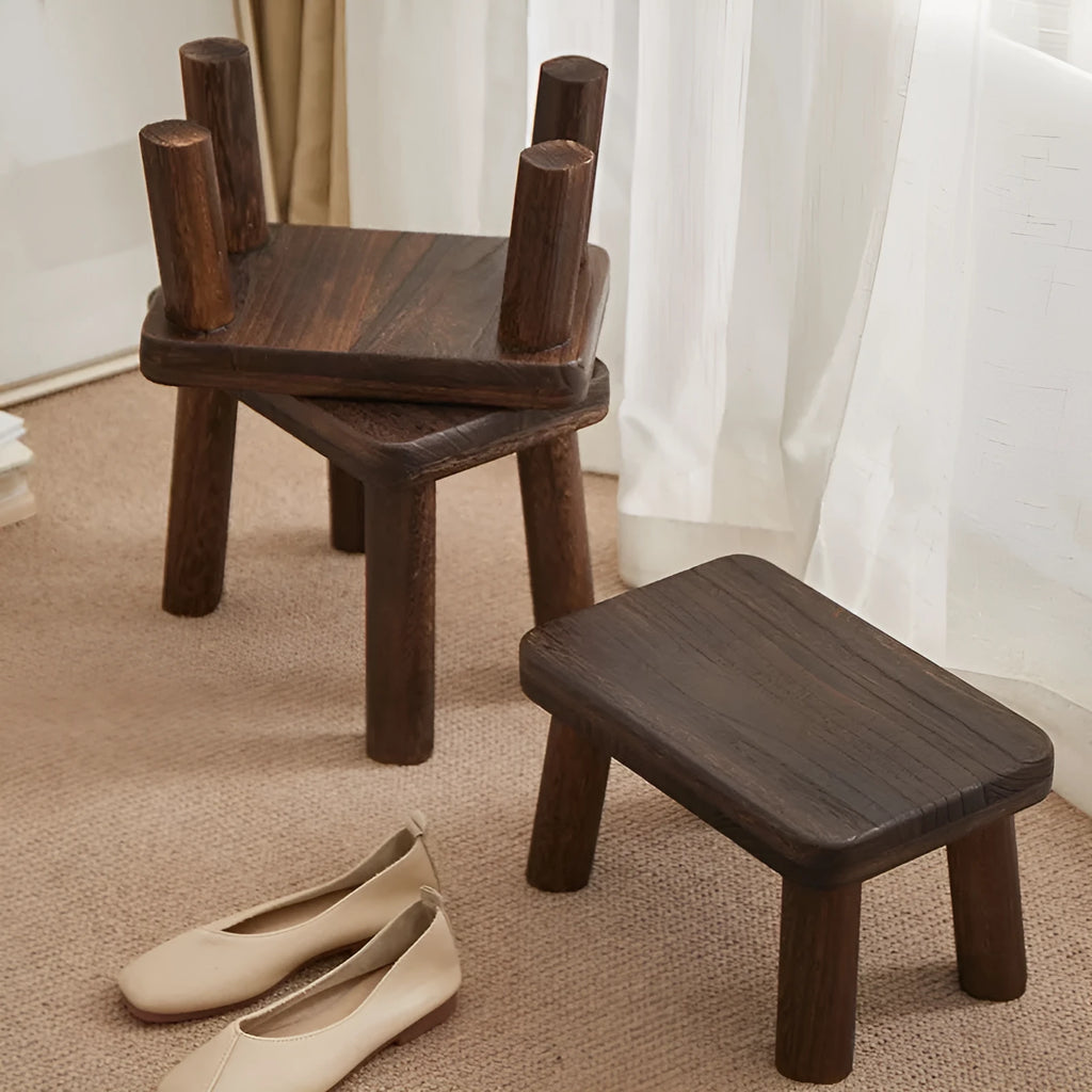 Distressed solid wood shoe changing stool with rustic bracket structure.