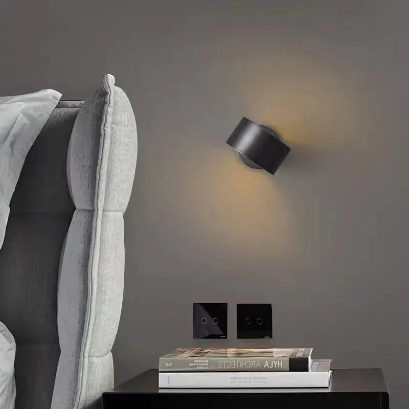 A simple modern copper wall lamp on a wall, shown in a black finish.