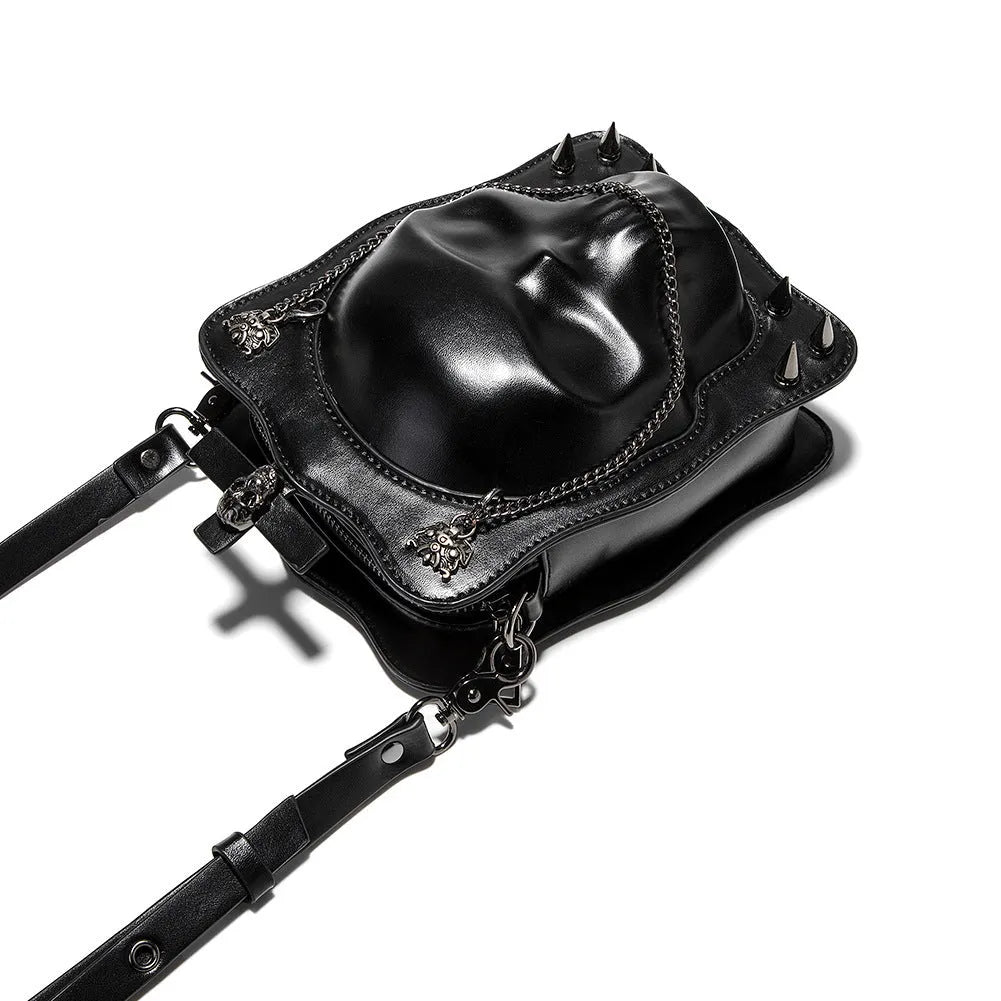 Black mini square crossbody bag with embossed skull design, metal chain strap, and zip closure.