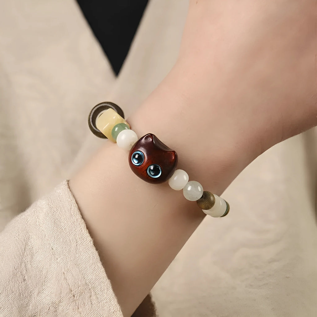 Hand-woven adjustable bracelet with bodhi seeds, jade beads, and a cartoon cat's paw guajacwood charm