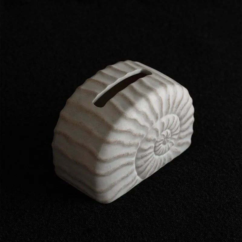 White conch ramble shell design resin tissue box holder on a table.