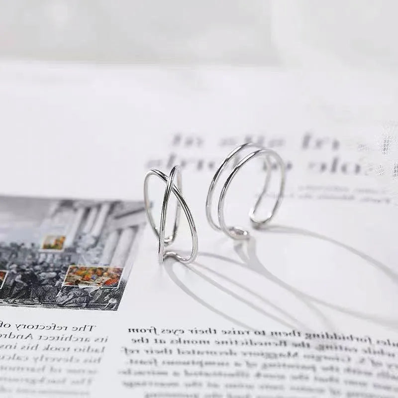 Silver plated geometric cross ring with an adjustable opening on a copper base.