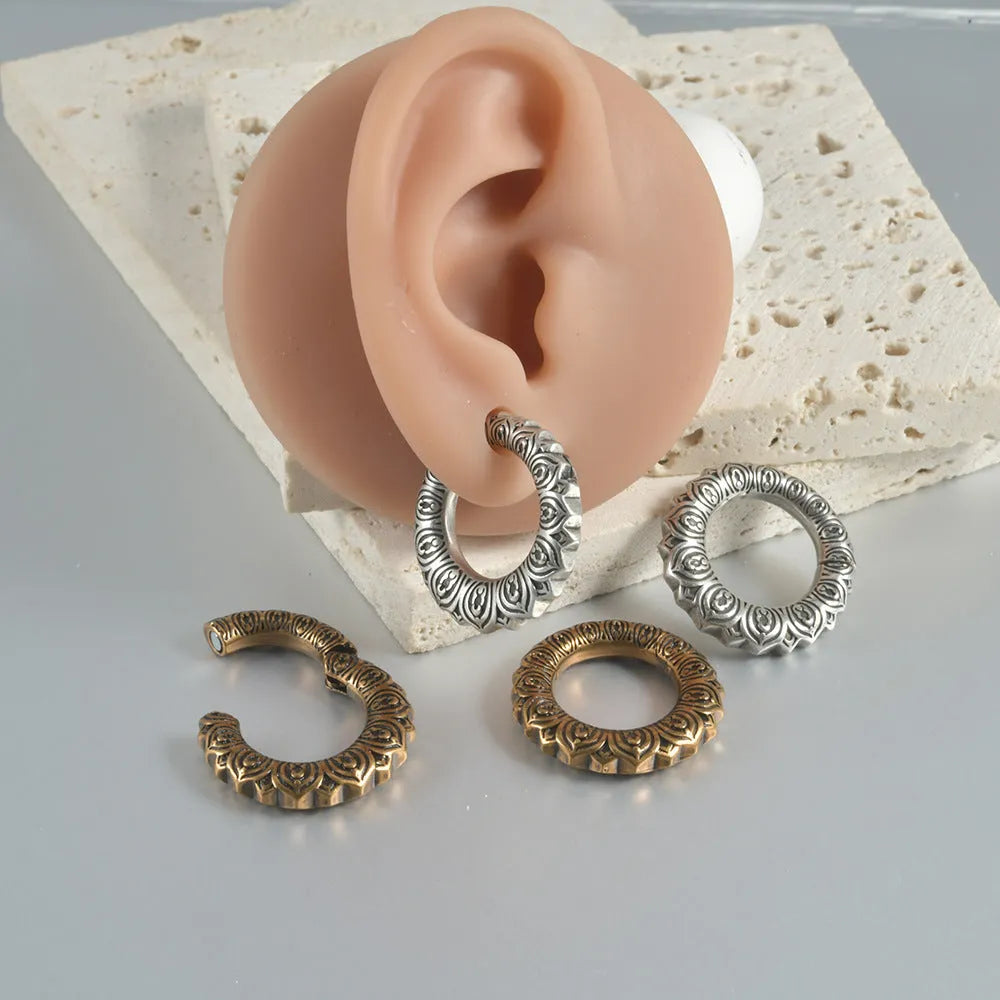 Pair of antique silver dragon-shaped hollow-out earrings with geometric design on a white background