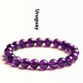 Close-up of a polished natural amethyst bead bracelet with a sliding knot closure on a wrist.
