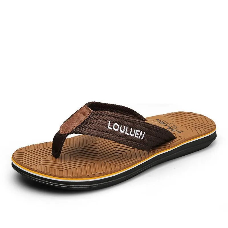Men's black flip flops with textured non-slip sole on a beach background.