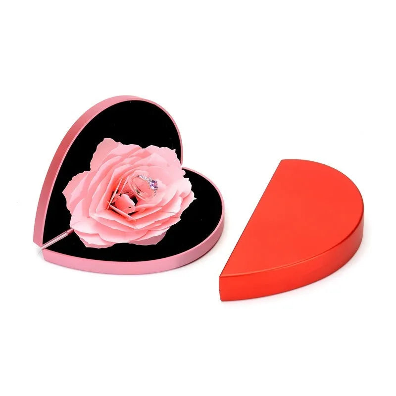 Red heart-shaped rotating ring box with 3D white rose decoration on top.