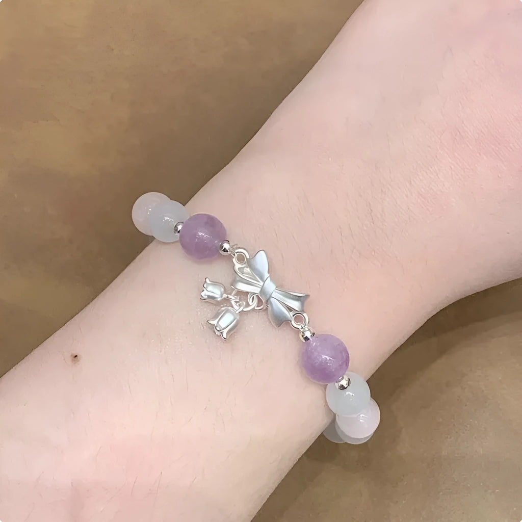 Lavender amethyst opal bracelet with a silver-toned bowknot design on a wrist.