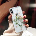 Clear iPhone case with dried pink Qianliyao flowers preserved in epoxy resin on transparent TPU back