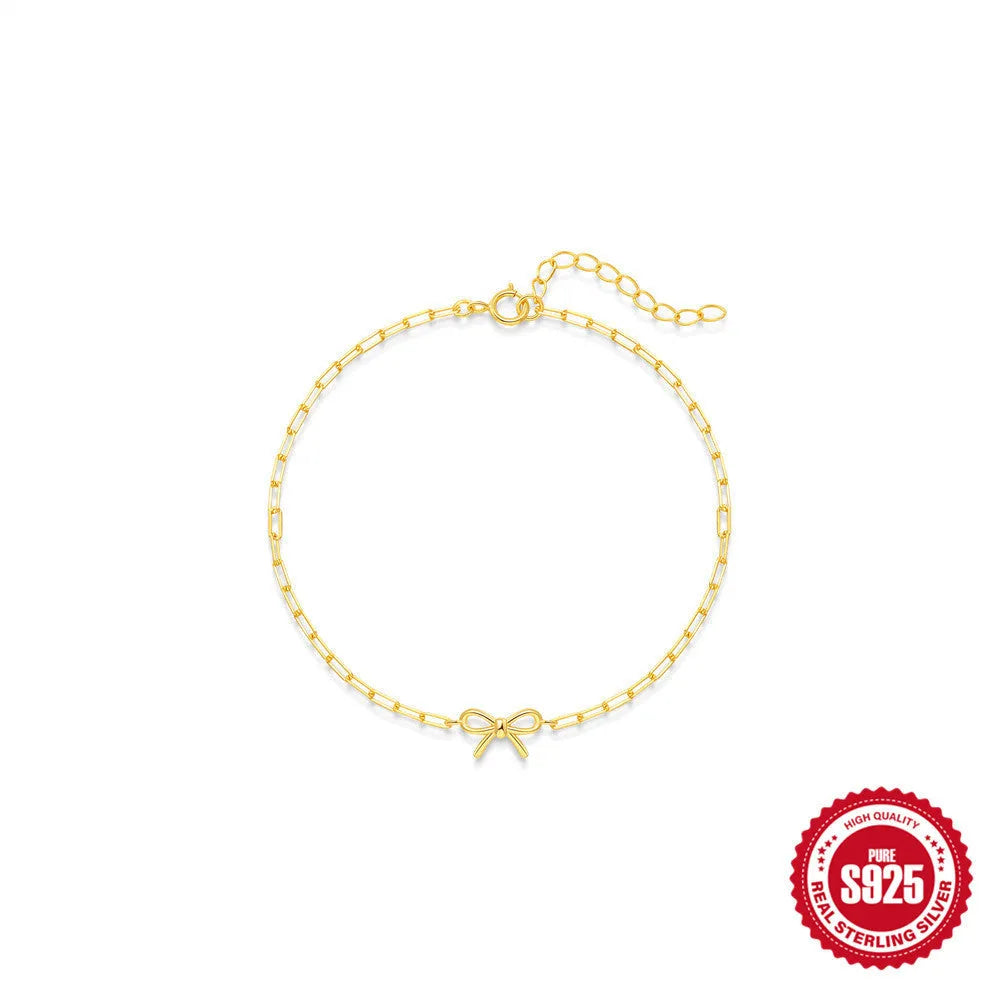 Close-up of a women's sterling silver bracelet with a glossy gold heart charm and lobster clasp.
