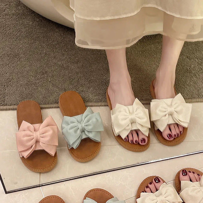Women's beige slip-on sandals with bow detail and flat rubber sole
